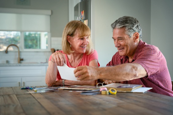 A Veteran couple makes a scrapbook on their dining room table.