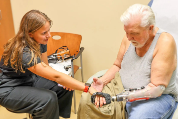A medical professional helps a VA tech use their prosthetic.